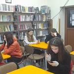 uczniowie piszący szkolny konkurs w bibliotece.jpg