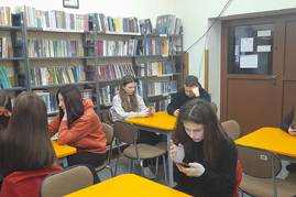 uczniowie piszący szkolny konkurs w bibliotece.jpg