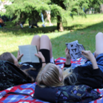 Uczennice czytają książki leżąc na kocyku.png