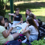 Uczniowie szkoły podstawowej czytają na trawie.png